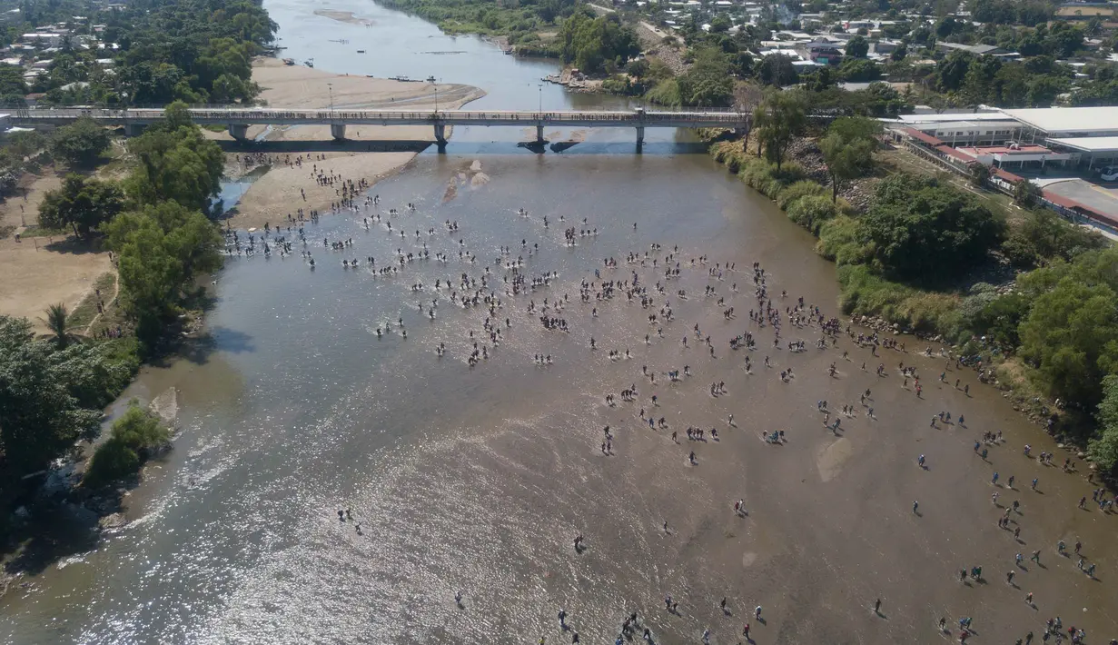 Migran Amerika Tengah menyeberangi Sungai Suchiate dengan berjalan kaki dari Guatemala ke Meksiko, Tecun Uman, Guatemala, Senin (20/1/2020). Lebih dari seribu migran Amerika Tengah yang terdampar di Guatemala berjalan massal untuk menuju Amerika Serikat. (AP Photo/Santiago Billy)