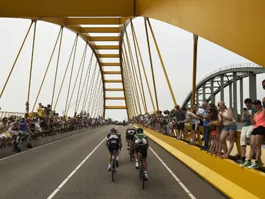 Para pebalap sedang melewati sebuah jembatan di Etape 2 Tour de France yang berjarak 166 km antara Utrecht dan Vrouwenpolder, Belanda. (5/7/2015). (AFP PHOTO/LIONEL BONAVENTURE)