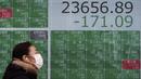 Seorang wanita berjalan melewati layar monitor yang menunjukkan indeks bursa saham Nikkei 225 Jepang dan lainnya di sebuah perusahaan sekuritas di Tokyo, Senin (10/2/2020). Pasar saham Asia turun pada Senin setelah China melaporkan kenaikan dalam kasus wabah virus corona. (AP Photo/Eugene Hoshiko)