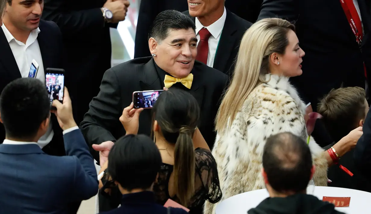 Legenda sepak bola Argentina Diego Maradona ditemani kekasihnya, Rocio Oliva saat menghadiri undian Piala Dunia 2018 di Moskow, Rusia (1/12). (AP Photo/Pavel Golovkin)