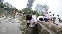Seorang anak mengambil air wudhu memanfaatkan air di kolam Putaran Patung Kuda, Jakarta, Jumat (4/11). Sebagian massa demonstan gelar salat Jumat di area Bundaran Patung Kuda. (Liputan6.com/Yoppy Renato)