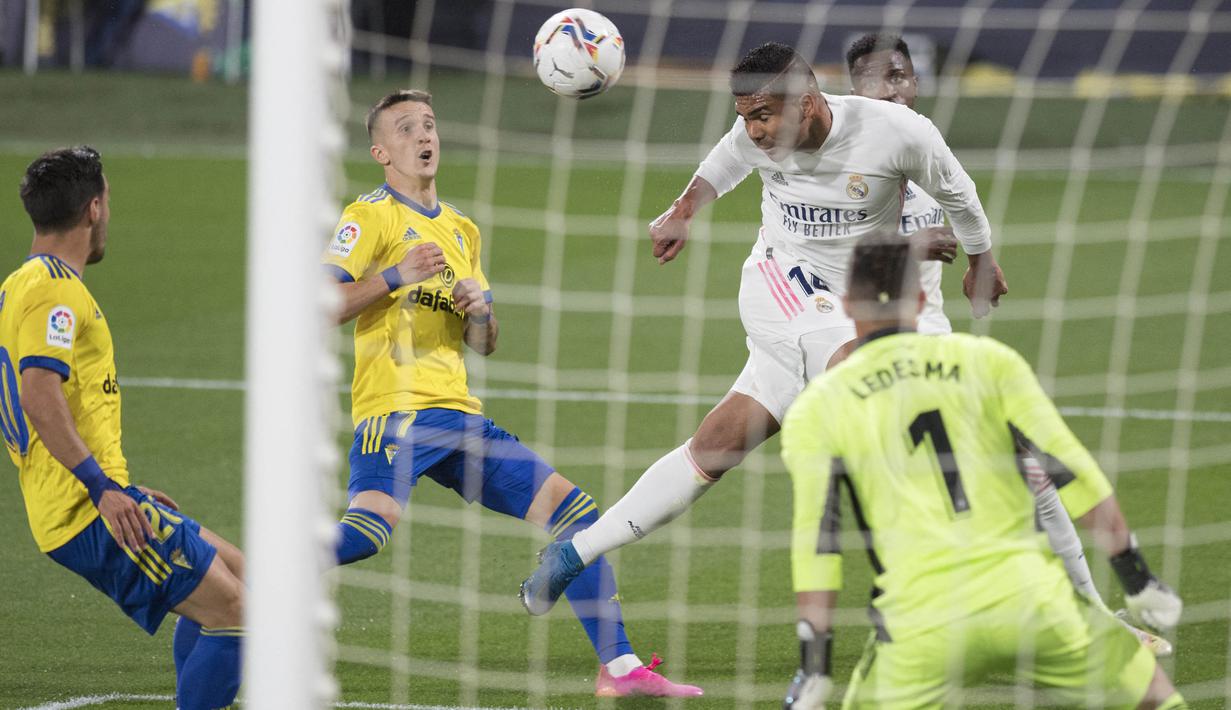 Gelandang Real Madrid, Casemiro, menyundul bola saat melawan Cadiz pada laga Liga Spanyol di Stadion Ramon de Carranza, Rabu (22/4/2021). Real Madrid menang dengan skor 3-0. (AFP/Jorge Guerrero)