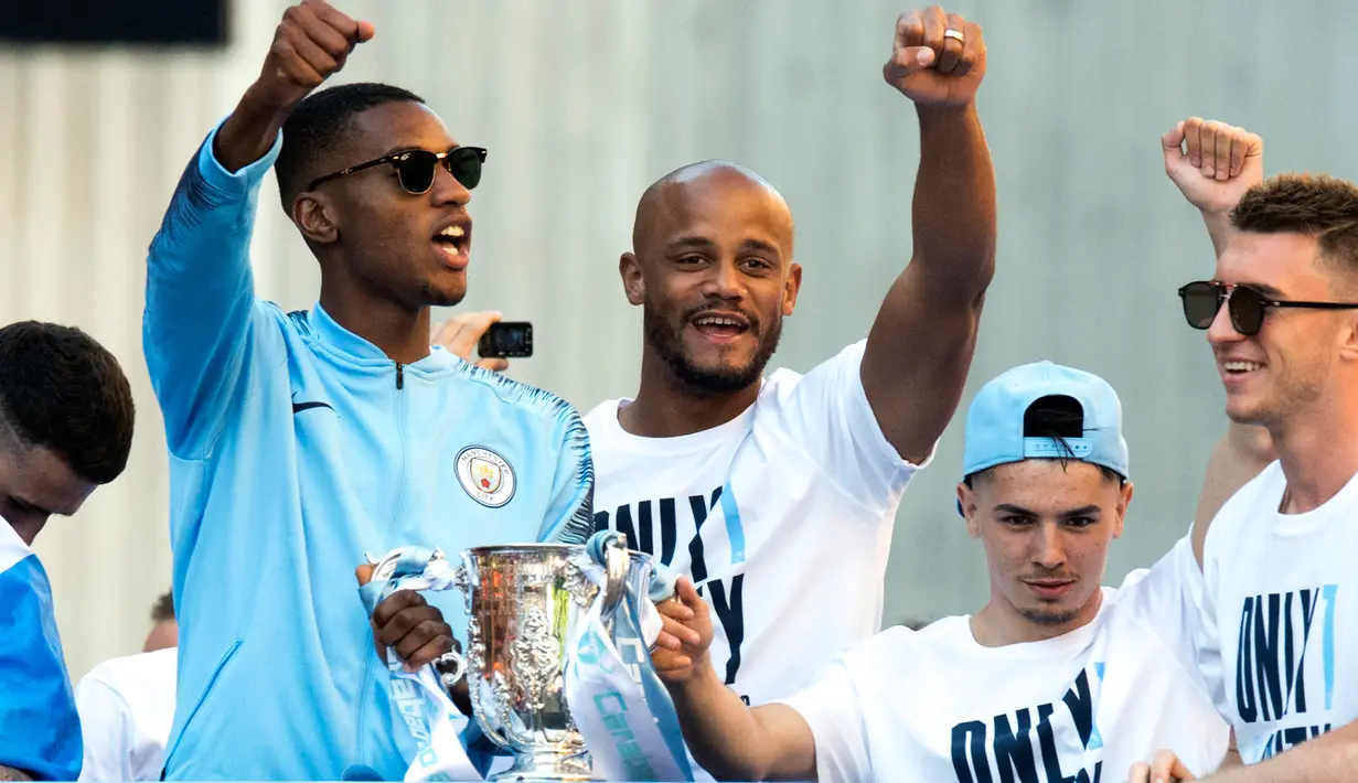 Kapten Manchester City, Vincent Kompany (tengah) bersama rekan setimnya melambaikan tangan dari atas bus beratap terbuka saat melakukan parade merayakan keberhasilan menjadi juara Liga Primer Inggris di Manchester, Senin (14/5). (Anthony Devlin/PA via AP)