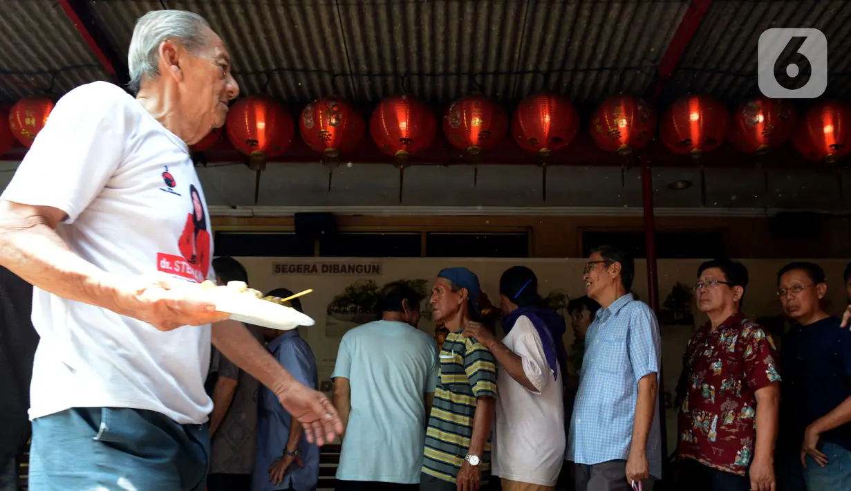 Warga mengantre saat membeli makan siang di warung nasi kuning Podjok Halal yang berada Vihara di Kim Tek Ie, Petak Sembilan, Jakarta, Selasa (24/12/2019). Warung Podjok Halal didirikan untuk menjangkau warga kurang mampu atau kaum duafa. (merdeka.com/Imam Buhori)