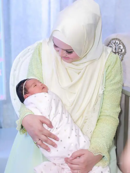 Penyanyi Siti Nurhaliza menggendong anak pertamanya Siti Aafiyah saat acara prosesi akikah. Anak tersebut merupakan anak pertama dari pernikahannya dengan Datuk Seri Khalid Mohamad. (instagram.com/ctdk)
