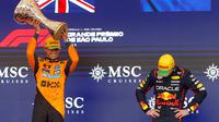 Pembalap Red Bull Racing, Max Verstappen (kanan) tertunduk saat pembalap McLaren, Lando Norrris mengangkat trofi kemenangan dalam Formula 1 GP Sao Paulo di Interlagos, Sao Paulo, Brasil, Minggu (09/11/2025). (AFP/Miguel Schincariol)