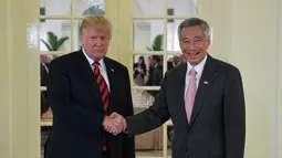 Presiden AS Donald Trump (kiri) berjabat tangan dengan PM Singapura Lee Hsien Loong (kanan) saat menerima jamuan makan siang di Istana Negara Singapura, Senin (11/6). Acara makan siang ini adalah agenda pertama Trump di Singapura. (SAUL LOEB/AFP)