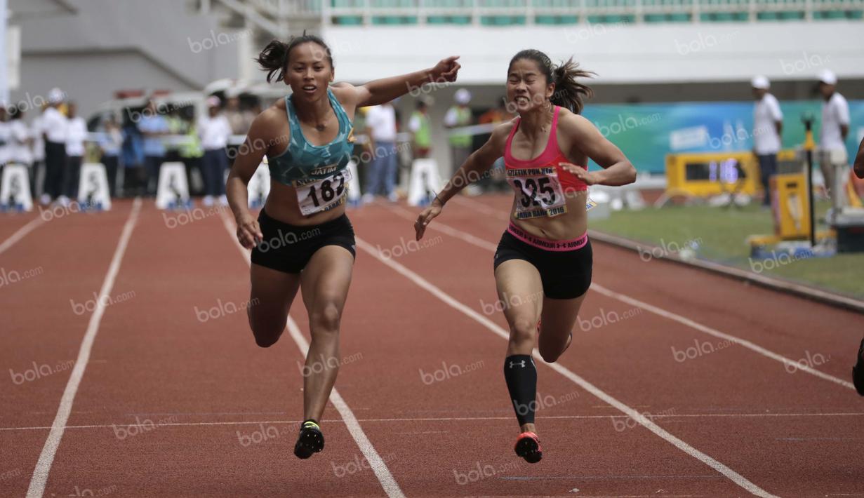 Atlet Jawa Timur, Tri Setyo Utami (kiri), meraih emas lari 100m putri PON XIX Jawa Barat 2016 setelah mengalahkan atlet Sumatra Barat, Lusiana Satriani (kanan) dalam final di Stadion Pakansari, Bogor, Kamis (22/9/2016). (Bola.com/Arief Bagus)