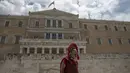 Seorang pria terlihat berdiri di depan gedung parlemen, sambil menggunakan pakaian tentara perang. Athena, Yunani (21/6/2015). (REUTERS/Marko Djurica)