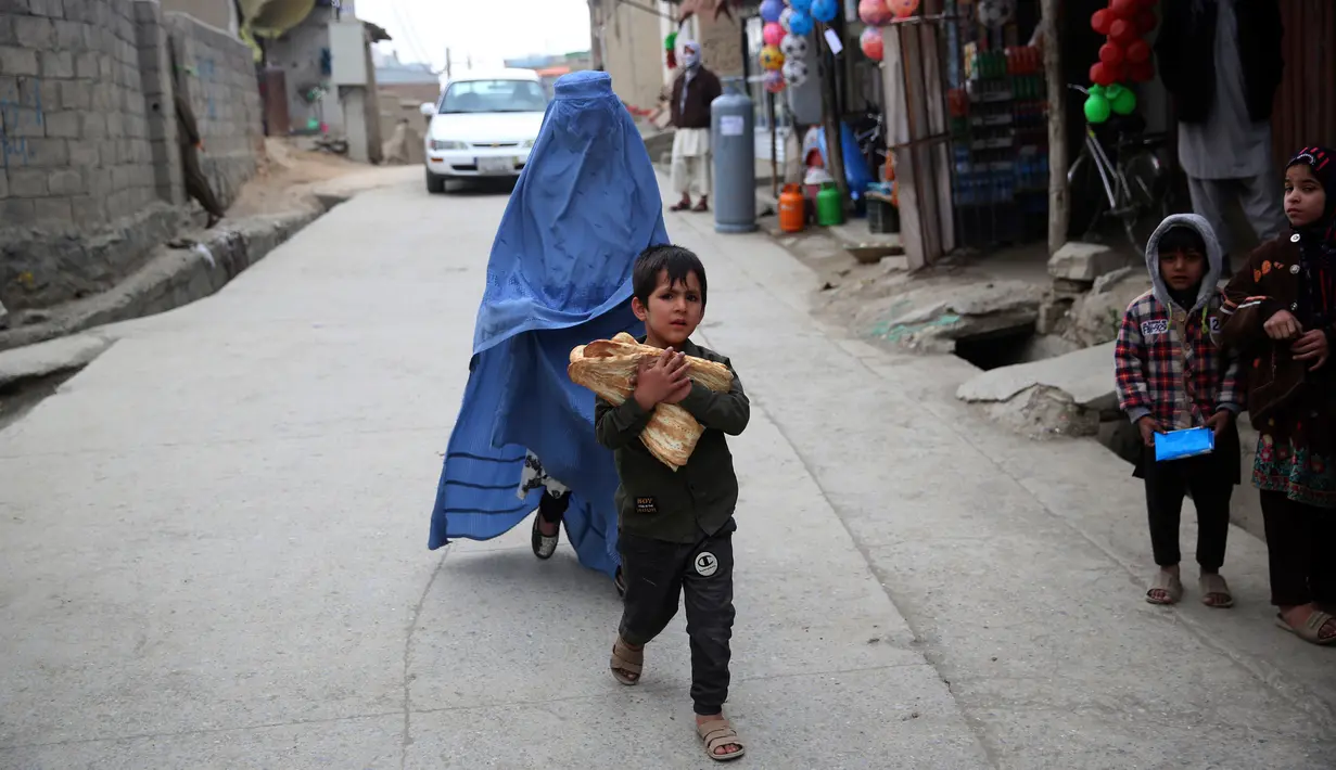 Seorang anak membawa roti gratis dari kota selama lockdown untuk mencegah penyebaran virus corona, pada bulan suci Ramadan di Kabul, Afghanistan (4/5/2020). Muslim di seluruh dunia sedang menjalankan Ramadan, ketika mereka menahan diri dari makan, minum dari subuh hingga senja. (AP/Rahmat Gul)