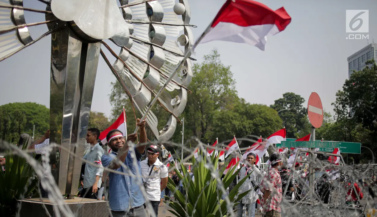 Massa Aliansi Masyarakat Indonesia Timur mengibarkan bendera Merah Putih saat berunjuk rasa di depan Istana Merdeka, Jakarta, Senin (2/9/2019). Massa menyatakan bahwa Papua tetap NKRI dan meminta pemerintah mengusut tuntas kasus rasis yang berujung konflik. (Liputan6.com/Faizal Fanani)