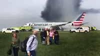 Sejumlah penumpang dievakuasi  saat pesawat American Airlines yang terbakar di Bandara O'Hare Chicago, Illinois, AS (28/10). (Jose Castillo via AP)
