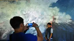 Pengunjung berfoto di salah satu lukisan yang berada di pameran “Pintu Belakang | Derau Jawa" di Galeri Nasional Indonesia, Jakarta (12/3). Pameran ini hasil karya Hanafi yang berasal dari Jawa. (Liputan6.com/Faisal R Syam)