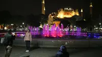Warga berfoto dengan latar belakang Hagia Sophia era Bizantium di Distrik Sultanahmet, Istanbul, Turki, Kamis (29/4/2021). Presiden Turki Recep Tayyip Erdogan memberlakukan "penguncian penuh" hingga 17 Mei di tengah melonjaknya infeksi dan kematian akibat COVID-19. (AP Photo/Emrah Gurel)