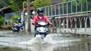 Seorang pria mengendarai sepeda motor di sebuah jalan yang terendam banjir pascahujan lebat di Bangkok, Thailand (31/8/2020). (Xinhua/Rachen Sageamsak)