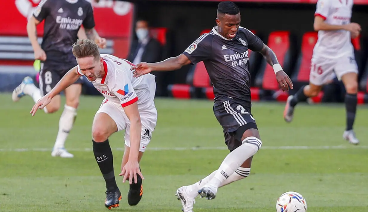 Penyerang Real Madrid, Vinicius Junior, berebut bola dengan pemain Sevilla, Luuk de Jong, pada laga Liga Spanyol di Stadion Ramon Sanchez Pizjuan, Minggu (6/12/2020). Real Madrid menang dengan skor 1-0. (AP/Angel Fernandez)