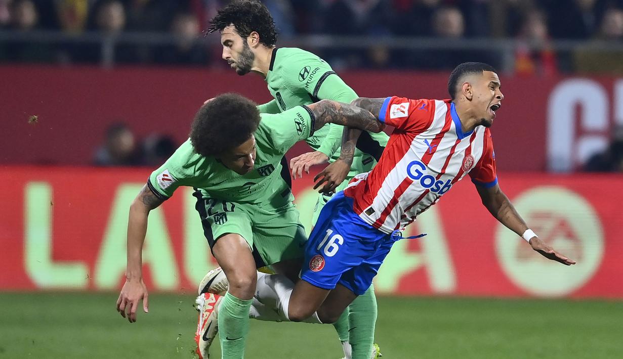 Gelandang Girona, Savio Moreira (kanan) ditekel gelandang Atletico Madrid, Axel Witsel saat perebutan bola pada laga pekan ke-19 Liga Spanyol 2023/2024 di Montilivi Stadium, Girona, Kamis (4/1/2024) dini hari WIB. (AFP/Pau Barrena)