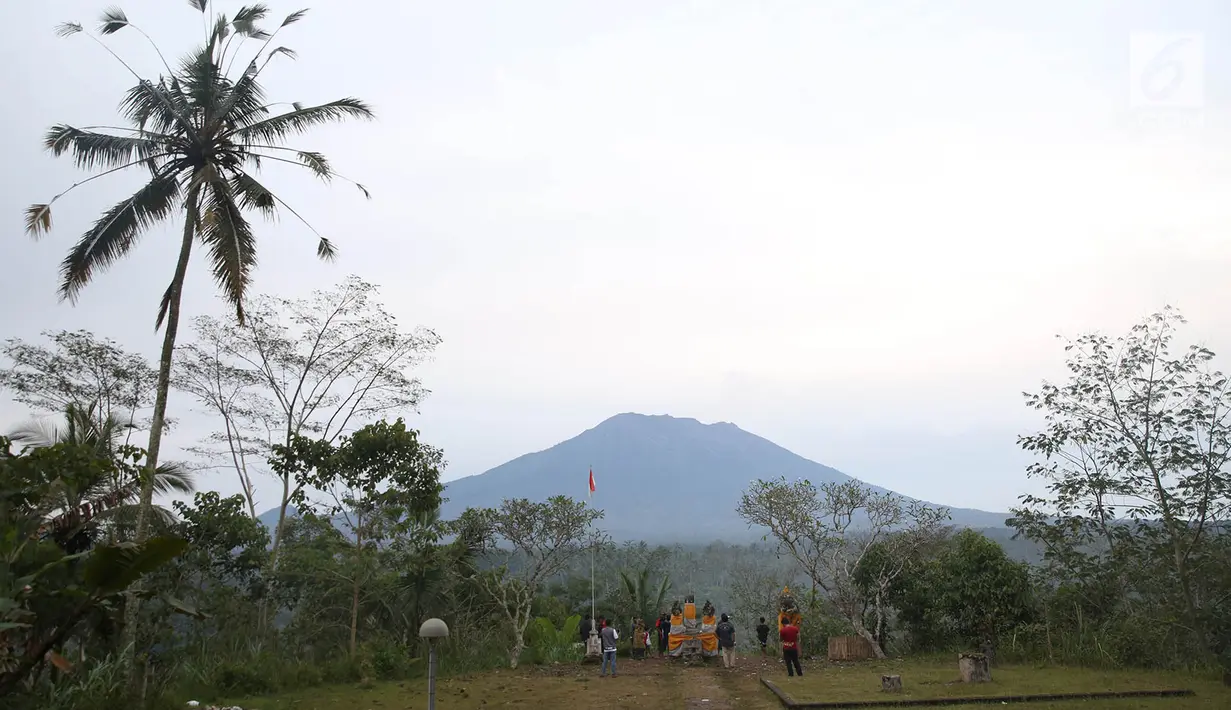 Sejumlah warga mengamati kondisi Gunung Agung, kawasan Karangasem, Bali, Sabtu (2/12). Hingga hari ini, penampakan asap dari kawah Gunung Agung semakin berkurang dibanding beberapa hari lalu. (Liputan6.com/Immanuel Antonius)
