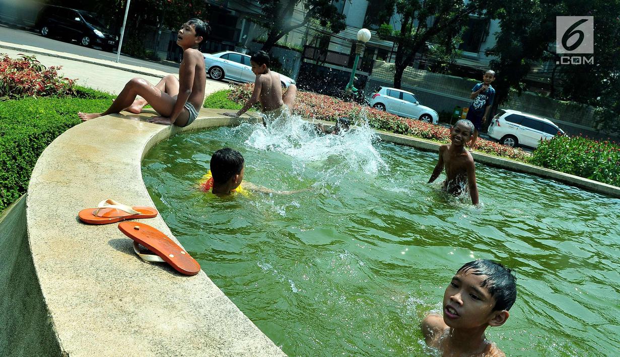 Sejumlah anak mandi bermain di bundaran air mancur Jalan Teuku Umar, Jakarta Pusat, Sabtu (23/9). Cuaca panas ibu kota memaksa anak-anak menceburkan diri di kolam untuk menyejukkan badan. (Liputan6.com/Helmi Afandi)