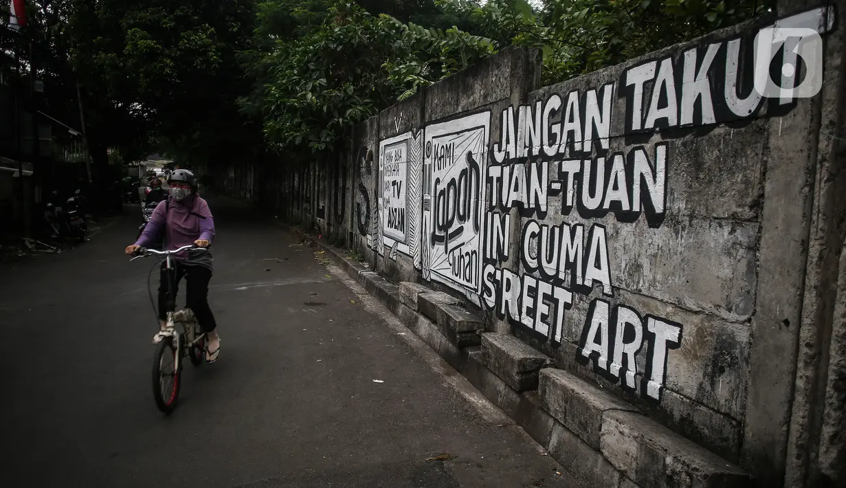 Pengendara sepeda melintas di depan mural di kawasan Jakarta Pusat. Selasa (24/8/2021). Banyak beberapa tempat mural yang menyuarakan kebebasan berpendapat saat ini menjadi viral lantaran dihapus oleh petugas. (Liputan6.com/Johan Tallo)