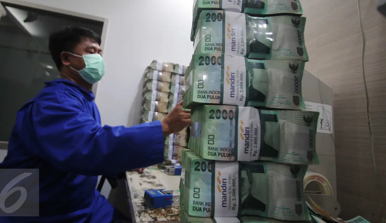 Petugas merapikan uang di Kantor Kas Bank Mandiri, Jakarta, Senin (4/1/2016). Nasib rupiah di tahun 2016 sulit menguat di tengah tingginya permintaan dollar. (Liputan6.com/Angga Yuniar)