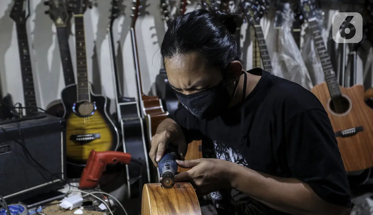 Harry saat mereparasi gitar klasik menjadi gitar listrik di toko kawasan Kedoya, Jakarta Barat, Selasa (9/2/2021). Turunnya servis gitar selama pandemi COVID-19 dikarenakan banyak pemilik gitar enggan untuk keluar rumah dan memilih untuk membeli gitar baru. (Liputan6.com/Johan Tallo)