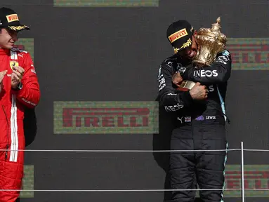 Pembalap Mercedes, Lewis Hamilton (kanan) berhasil meraih podium juara F1 GP Inggris, Minggu (18/7/2021) malam WIB. Sedangkan pembalap Ferrari Charles Leclerc menempati posisi kedua dalam balapan tersebut. (Foto: AFP/Adrian Dennis)