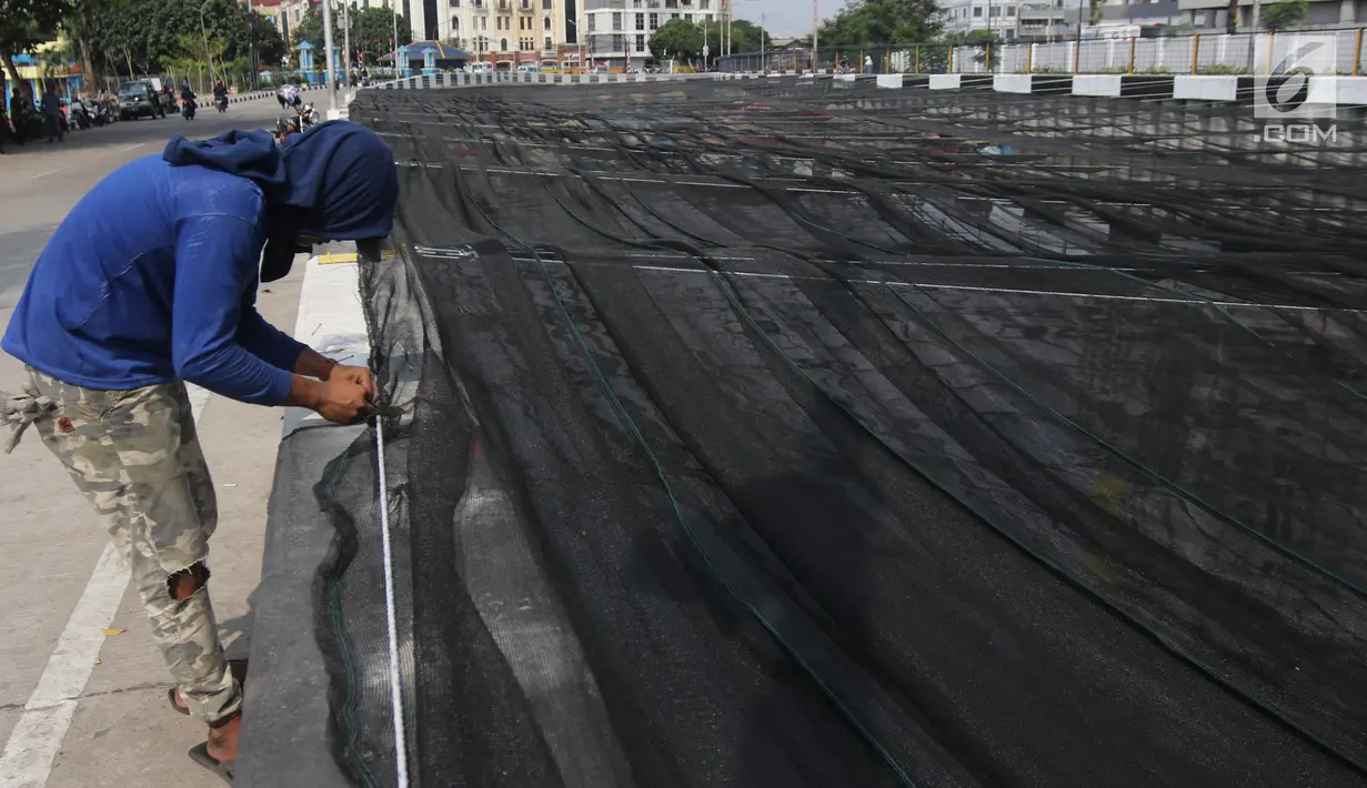 Petugas memasang jaring hitam di Kali Item, Kemayoran, Jakarta, Jumat (20/7). Pemasangan jaring tersebut merupakan cara Pemprov DKI mengatasi bau sebelum menerima atlet Asian Games 2018 yang akan menginap di Wisma Atlet. (Liputan6.com/Arya Manggala)