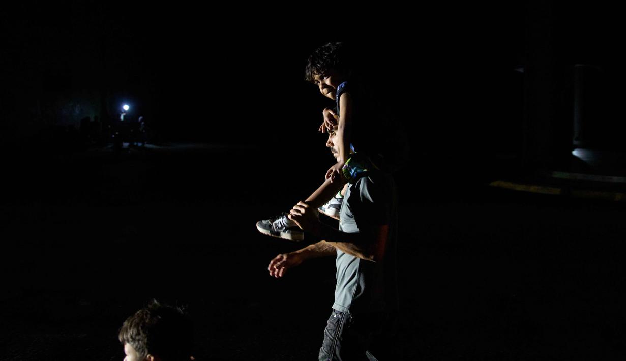 Pemerintah menyebut proses pemulihan sedang dilakukan secara bertahap. Tampak dalam foto, seorang pria dan seorang anak menyeberang jalan saat pemadaman listrik di Havana, Kuba, Rabu 4 Maret 2026. (AP Photo/Ramon Espinosa)