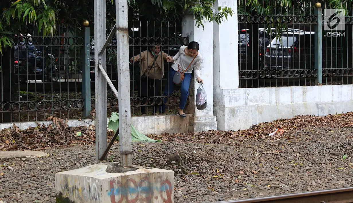 Warga menerobos pagar untuk menyeberangi rel kereta api di kawasan Lenteng Agung, Jakarta, Selasa (19/3). Tidak adanya JPO menyebabkan warga harus menerobos pagar besi, meskipun perilaku tersebut berbahaya bagi keselamatan.(Liputan6.com/Immanuel Antonius)