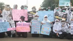 Massa dari Forum Komunikasi Nakes dan Non-Nakes Indonesia (FKHN Indonesia) membawa poster tuntutan saat menggelar aksi di kawasan Patung Kuda, Jakarta Pusat, Kamis (22/9/2022). Selain mengenakan pakaian berwarna putih, massa aksi juga terlihat membawa sejumlah atribut. (Liputan6.com/Herman Zakharia)