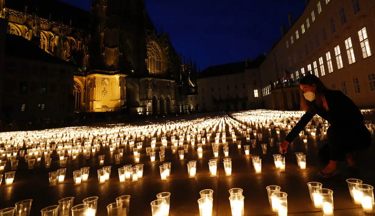 Seorang wanita menyalakan lilin untuk memperingati para korban pandemi virus corona COVD-19 di Kastil Praha, Praha, Republik Ceko, Senin (10/5/2021). Republik Ceko melonggarkan pembatasan terkait COVID-19 secara besar-besaran kendati hampir 30 ribu orang telah meninggal. (AP Photo/Petr David Josek)