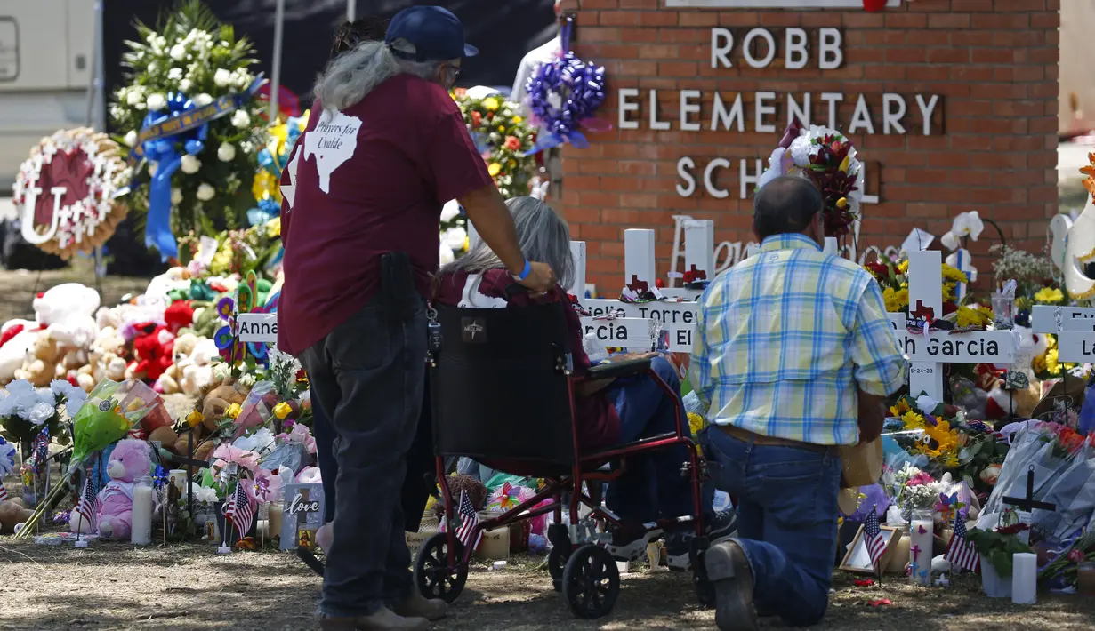 Orang-orang memberikan penghormatan dalam sebuah peringatan di luar Robb Elementary School untuk menghormati para korban yang tewas dalam penembakan di sekolah pekan ini di Uvalde, Texas, Amerika Serikat, 28 Mei 2022. (AP Photo/Dario Lopez-Mills)