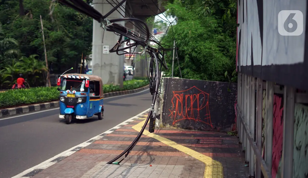 Bajaj melintas di samping instalasi kabel yang semrawut di Jalan Kyai Maja, Kebayoran Baru, Jakarta Selatan, Rabu (11/11/2020). Kurangnya penataan menjadi penyebab instalasi kabel di Ibu Kota kian semrawut sehingga mengganggu kenyamanan serta keselamatan warga. (Liputan6.com/Immanuel Antonius)