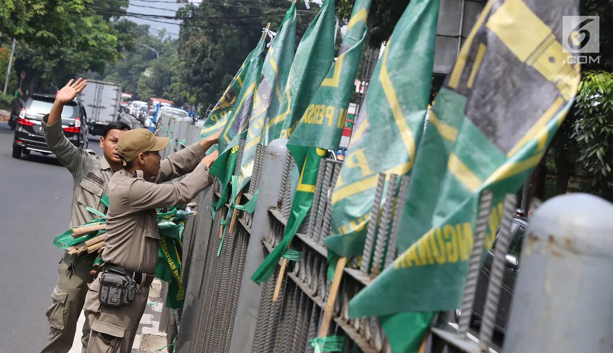 Petugas Satpol PP mencopot bendera partai politik di sepanjang pagar kawasan Pancoran, Jakarta. Selasa (18/7). Pencopotan dilakukan untuk menertibkan bendera partai politik liar yang memenuhi ruang publik di Ibukota. (Liputan6.com/Immanuel Antonius)