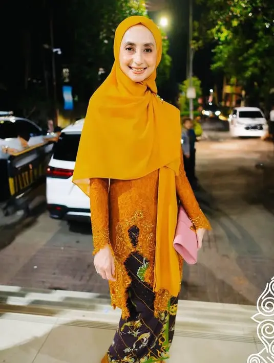 Atasan tersebut dipadukan bawahan kain batik coklat. Ia juga membawa clutch warna pink. [@official_amteam]