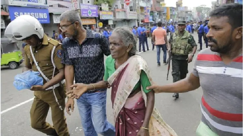 Seorang wanita tua dibantu menyelamatkan diri pasca-ledakan di St. Anthony, Sri Lanka ( Eranga Jayawardena / AP )