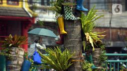 Sepatu bot dijadikan pot hias tanaman di kawasan Kota Tua, Jakarta, Jumat (7/8/2020). Lahan tersebut dipercantik dengan hiasan pot dari sepatu bot yang diwarnai untuk mempercantik lahan kosong di Ibu Kota. (merdeka.com/Imam Buhori)