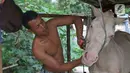 Pekerja membersihkan kuda di kampung delman kawasan Menteng Dalam, Jakarta, Senin (27/9/2021). Para pekerja delman berharap pelonggaran PPKM membawa harapan mereka untuk kembali bekerja normal seperti biasanya. (Liputan6.com/Herman Zakharia)
