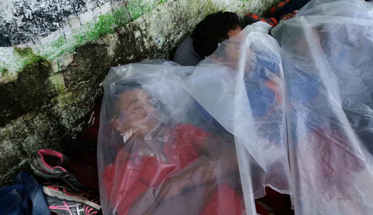 Imigran Honduras yang sedang menuju Amerika Serikat tidur menggunakan sepotong plastik di trotoar di Huixtla, Meksiko, 23 Oktober 2018. Presiden AS Donald Trump mengerahkan militer untuk menghalau para imigran. (AP Photo/Moises Castillo)