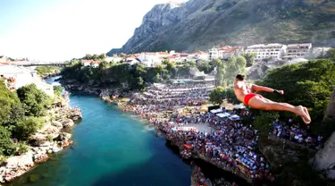 Peserta pria beraksi dengan melompat dari jembatan saat mengkuti acara kompetisi menyelam tradisional 450 di Mostar, Bosnia dan Herzegovina, (31/7). (REUTERS/Dado Ruvic)