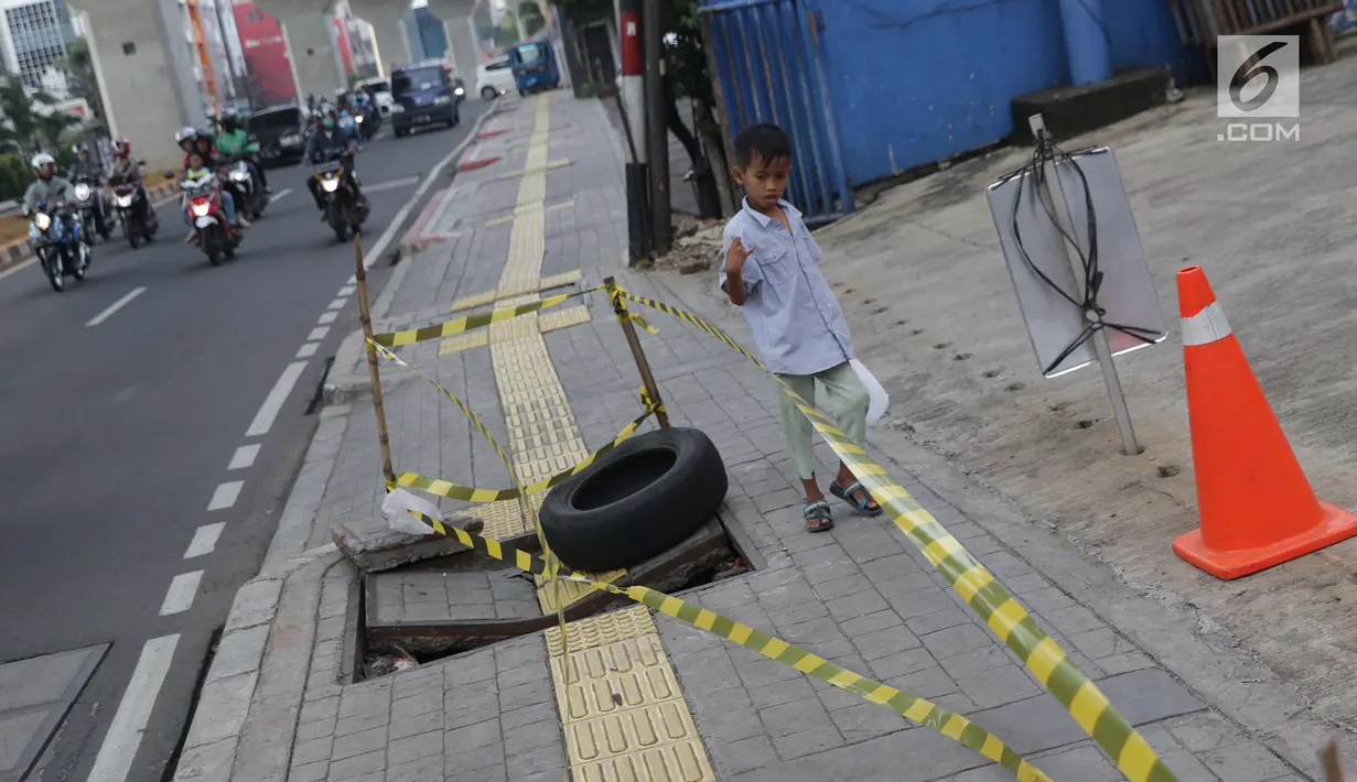 Seorang anak melintas di sisi penutup trotoar yang rusak di Jalan RS Fatmawati, Jakarta, Selasa (14/7/2019). Dua buah penutup trotoar di Jalan RS Fatmawati rusak parah, kondisi ini mengganggu kenyamanan dan membahayakan pejalan kaki, terutama pada malam hari. (Liputan6.com/Helmi Fithriansyah)