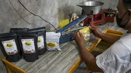 Seorang pria mengepak biji kopi robusta, dipanggang menggunakan metode tradisional Aceh sebagai bagian dari usaha kecil, di Krueng Barona Jaya di provinsi Aceh (21/2/2022). (AFP/Chaideer Mahyuddin)