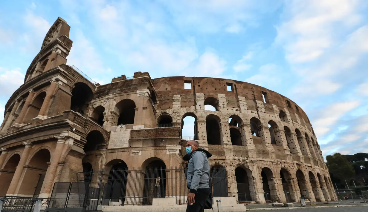 Seorang pria berjalan melewati Colosseum di Roma, Italia (4/11/2020). Museum, galeri, teater, balai konser, bioskop, dan tempat perjudian harus ditutup, sementara pertemuan publik, perayaan, pameran, festival, dan berbagai acara, baik outdoor maupun indoor, dilarang. (Xinhua/Cheng Tingting)