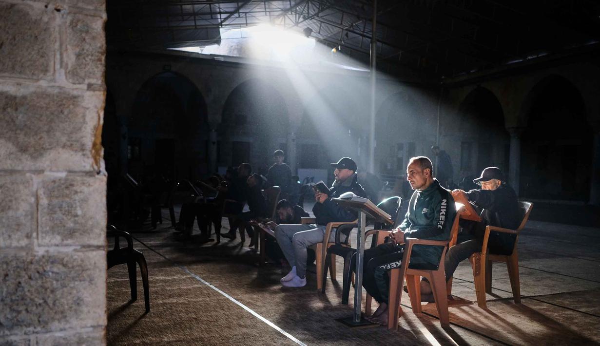 Meski berlangsung di tengah kesepakatan gencatan senjata antara Israel dan Hamas yang dimulai sejak Oktober 2025, situasi tetap rapuh karena adanya beberapa pelanggaran dan keterbatasan sumber daya yang ekstrem. Tampak dalam foto, warga Palestina membaca Al-Quran selama bulan suci Ramadan di Masjid Sayed Al-Hashim, Kota Gaza, Kamis 19 Februari 2026. (AP Photo/Jehad Alshrafi)