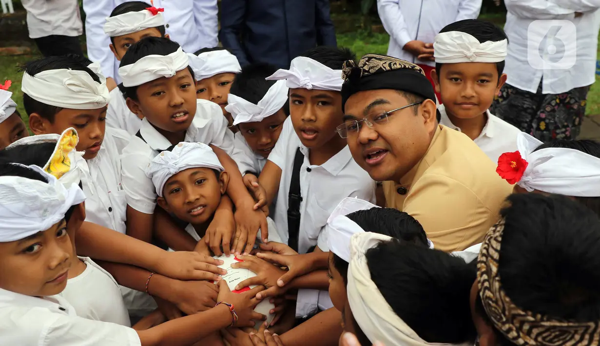 Deputi Bidang SDM, Teknologi, dan Informasi Kementerian BUMN, Tedi Bharata (kedua kiri) menyerahkan bola untuk anak-anak desa Penglipuran, Kabupaten Bangli, Bali, Kamis (17/8/2023). (Liputan6.com/Helmi Fithriansyah)
