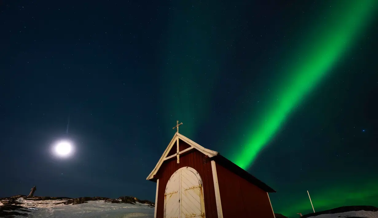 Sebagai informasi, Aurora Borealis merupakan salah satu fenomena langit yang paling diburu oleh pencinta alam dan astronomi. Tampak dalam foto, Aurora borealis menerangi langit malam di atas sebuah pondok kecil di Nuuk, Greenland, pada 23 Januari 2026. (Jonathan NACKSTRAND/AFP)