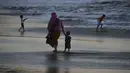 Seorang wanita bersama putranya berjalan di tepi pantai saat matahari terbenam di Banda Aceh pada 28 Juni 2019. Suasana eksotis menuju temaram bisa dinikmati sembari berjalan menyusuri pantai di tengah cahaya matahari yang mulai memerah. (Photo by CHAIDEER MAHYUDDIN / AFP)