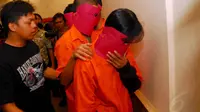 Para tersangka yang memakai baju tahanan berwarna orange menutupi wajahnya dengan topeng yang terbuat dari karton merah. (Liputan6.com/ Miftahul Hayat)
