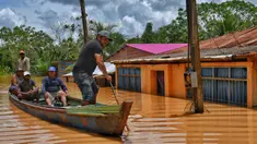 Orang-orang menaiki rakit di daerah yang terendam banjir setelah Sungai Acre meluap di Cobija, Bolivia, pada tanggal 29 Februari 2024. (STRINGER/AFP)